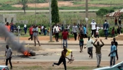 Protesters throw rocks at policemen during an attack on South African business in Abuja, Nigeria, Sept. 4, 2019.