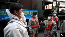 지난 12일 한국 서울에서 군인들이 신종 코로나바이러스 방역을 위해 거리에 소독액을 뿌리고 있다.