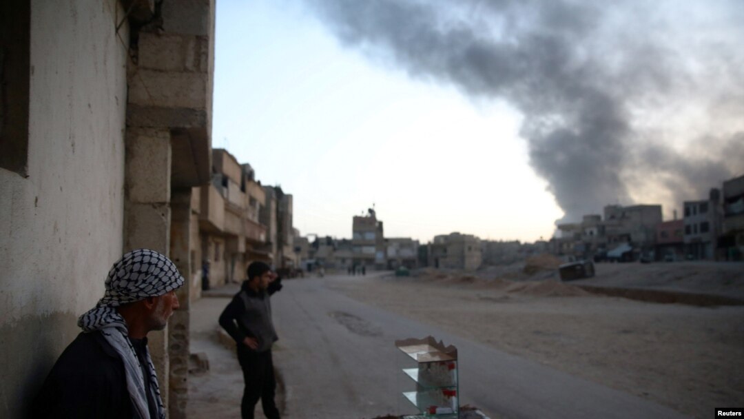Warga Suriah menyaksikan asap membumbung dari wilayah Harasta, seperti terlihat dari Douma, di timur Damascus, di pinggir kota Ghouta, Suriah, 14 November 2017. 