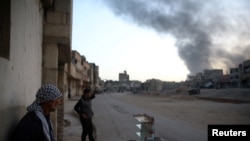 FILE - Syrian residents watch as smoke rises from Harasta area, as seen from Douma, in the eastern Damascus suburb of Ghouta, Syria, Nov. 14, 2017. 