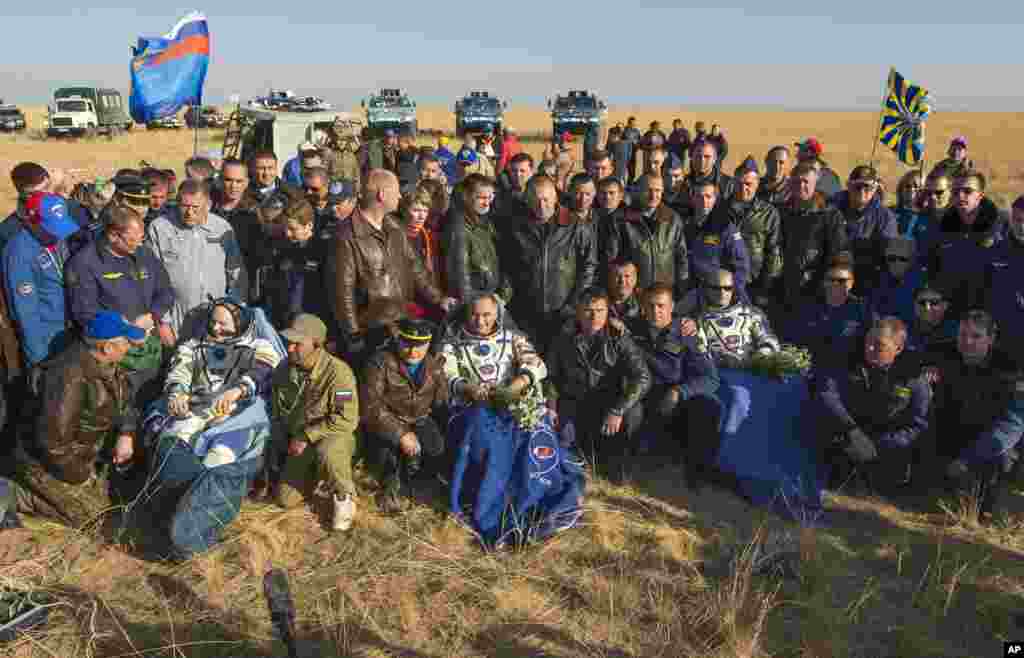 Expedition 40 Flight Engineer Oleg Artemyev of the Russian Federal Space Agency (Roscosmos), left, Flight Engineer Alexander Skvortsov of Roscosmos, center, and Expedition 40 Commander Steve Swanson of NASA, sit in chairs outside the Soyuz TMA-12M capsule