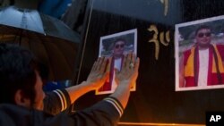 An exile Tibetan pastes on a pillar a portrait of Tsewang Norbu, 29, a Buddhist monk who died Monday after setting himself on fire in China's Sichuan province's Garze Tibetan Autonomous Prefecture during a candle light vigil in Dharmsala, India, Monday, A