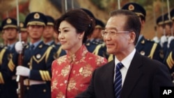 Chinese Premier Wen Jiabao, right, shows the way to Thai Prime Minister Yingluck Shinawatra as they review an honor guard during a welcome ceremony for her at the Great Hall of the People in Beijing, China, Tuesday, April 17, 2012. Shinawatra is leading a