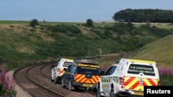 Emergency service vehicles ride along the tracks near the scene of a derailed passenger train, near Carmont, Stonehaven, Scotland, Britain, Aug. 12, 2020. 