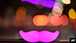 FILE - A Lyft Glowstache glows on the dashboard of a car in San Francisco, Feb. 3, 2016.