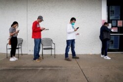 FILE - People who lost their jobs wait in line to file for unemployment following an outbreak of the coronavirus disease (COVID-19), at an Arkansas Workforce Center in Fayetteville, Arkansas, April 6, 2020.