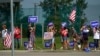 Sejumlah pendukung capres Partai Republik, Donald Trump, membawa sejumlah poster berisi dukungan saat rombongan Trump bergerak melewati wilayah mereka di Roseville, Michigan, pada 26 Agustus 2024. (Foto: AP/Carolyn Kaster)