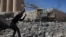 In this April 5, 2018 photo, workers remove rubble of a bridge that was destroyed last summer during fighting between U.S.-backed Syrian Democratic Forces fighters and Islamic State militants, in Raqqa, Syria. 
