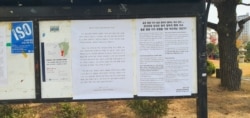 A poster announcing new school policies, and a poster opposing the school's decision. Hankuk University of Foreign Studies in Seoul on November 21, 2019. (VOA/Lee Juhyun)