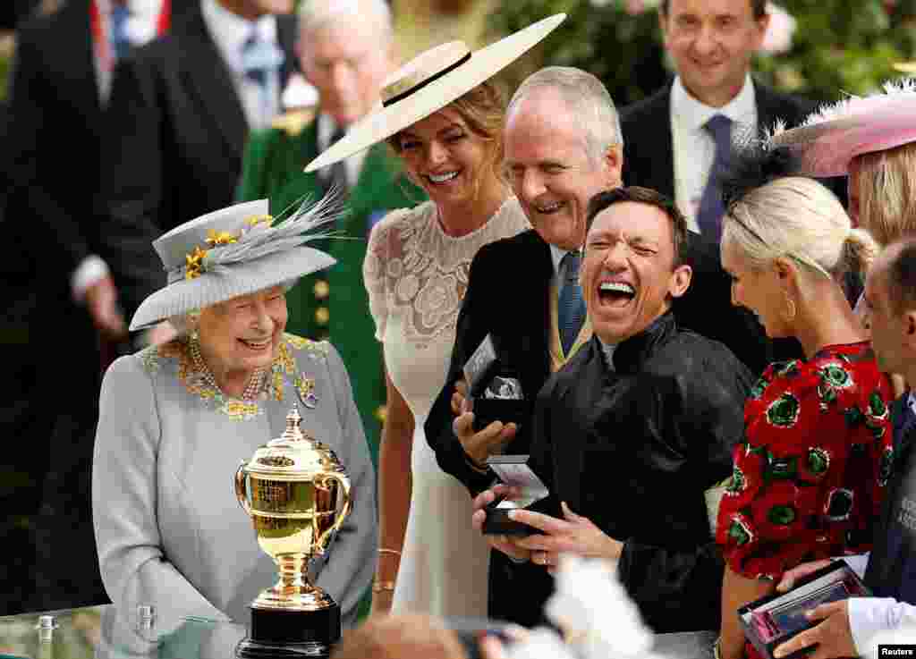 Britain&#39;s Queen Elizabeth II (L) watches as Italian jockey Frankie Dettori (R) celebrates with the trophy after he won the Gold Cup on horse Stradivarius, on day three of the Royal Ascot horse racing meet, in Ascot, west of London.