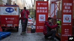 Pekerja pengiriman untuk raksasa e-commerce China JD.com, mendirikan titik pengumpulan paket "No Contact" sementara di luar kompleks apartemen di Beijing, China, 18 Februari 2020. (AP/Ng Han Guan)