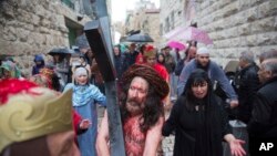 Un actor vestido como Jesucristo lleva una cruz al recrear su camino hacia la crucifixión en la Vía Dolorosa, en la Ciudad Vieja de Jerusalén, el viernes, 30 de marzo, de 2018, durante una tradición del Viernes Santo.
