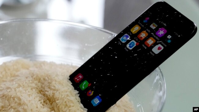 A view of a wet smartphone placed in a bowl of rice to dry, in London, Wednesday, Feb. 28, 2024. (AP Photo/Frank Augstein)