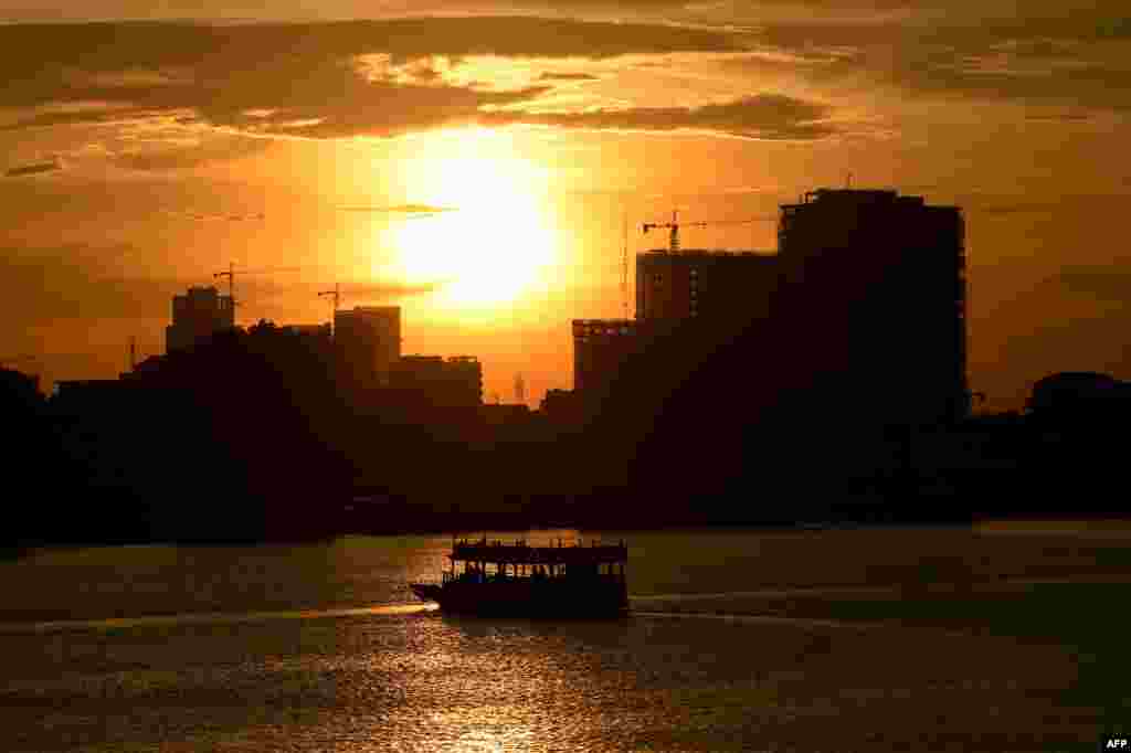 해가 지는 캄보디아 프놈펜의&nbsp;톤레삽 강을 따라 관광객들을 태운 배가 떠다니고 있다.