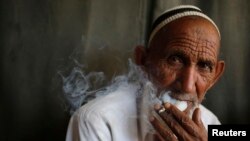 FILE - A man smokes a cigarette in a public place in the northern in the state of Uttar Pradesh, India, April 2014.