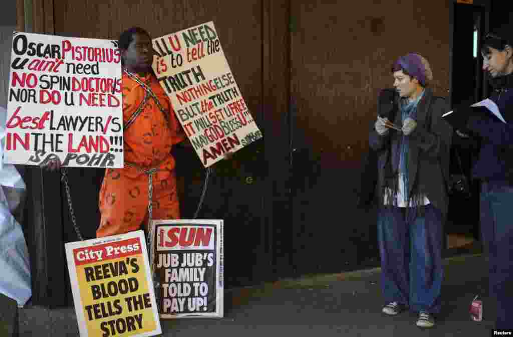 A man holds signs ahead of the court proceedings of Olympic and Paralympic athlete Oscar Pistorius at the Pretoria Magistrates court, August 19, 2013. 