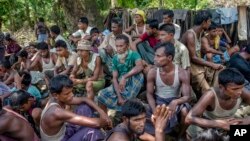 FILE - Rohingya Muslims from Myanmar wait to carry food items from Bangladesh's border toward a no man's land where they set up refugee camps, in Tombru, Bangladesh, Sept. 15, 2017. 