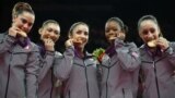U.S. gymnasts McKayla Maroney, Kyla Ross, Alexandra Raisman, Gabrielle Douglas and Jordyn Wieber bite their gold medals at the Artistic Gymnastics women's team final at the 2012 Summer Olympics, July 31, 2012, in London.