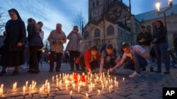 People light candles during a memorial service in front of the Muenster cathedral, in Muenster, Germany. April 8, 2018, one day after a man killed two people and injured 20 others by crashing into people outside a popular bar before killing himself. 