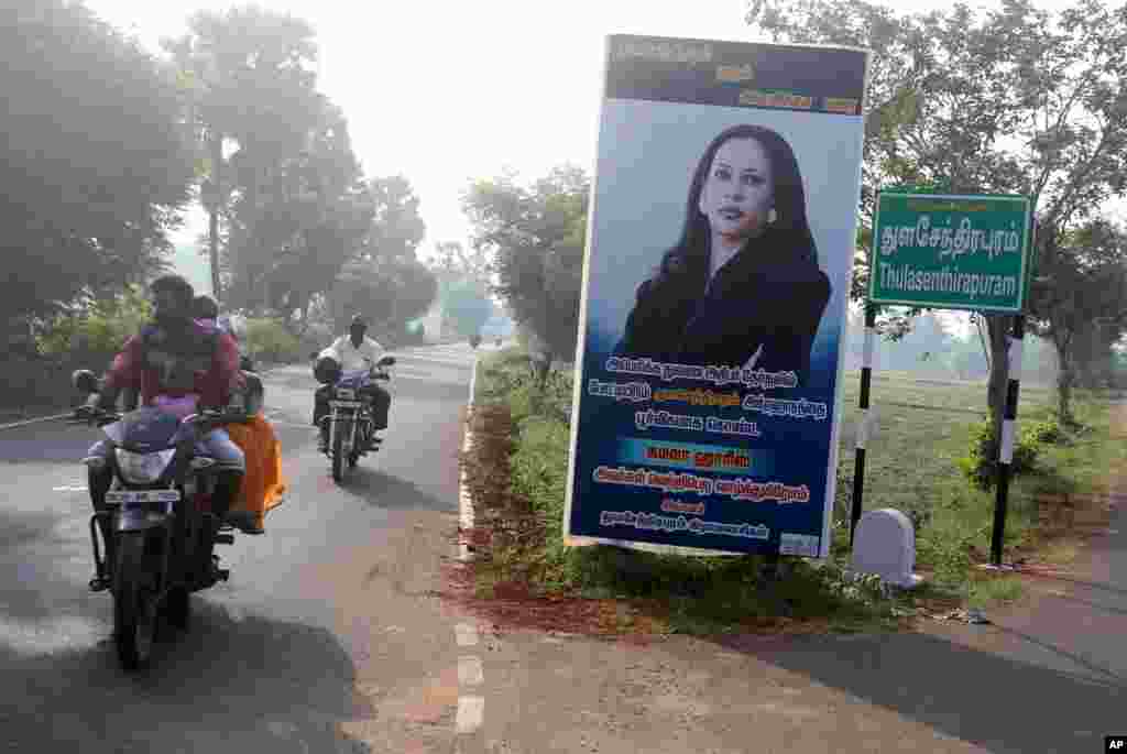 People ride past a billboard featuring U.S. democratic vice presidential candidate Sen. Kamala Harris, at a crossing in Thulasendrapuram village, Tamil Nadu state, India.