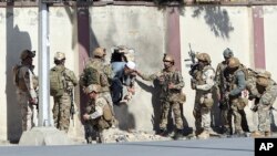 FILE - Afghan security personnel rescue a man from the Shamshad TV compound after an attack in Kabul, Nov. 7, 2017.