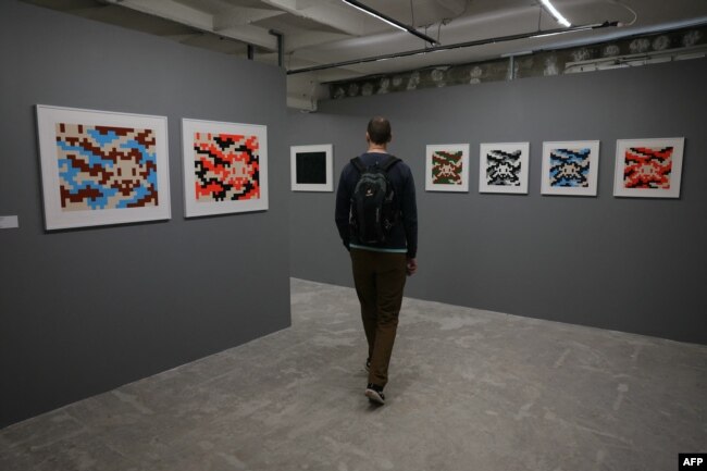 FILE - A man visits the "Space Invader Station" exhibition of street artist Invader in Paris, on February 27, 2024. (Photo by Thomas SAMSON / AFP) /