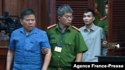This picture from the Vietnam News Agency taken and released on Nov. 11, 2019 shows Australian citizen Chau Van Kham (L) escorted for trial in Ho Chi Minh City.