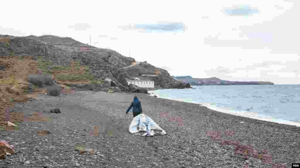 One of the team for Lighthouse Relief moves the remains of a dinghy from the shore of Skala Sikamineas. They are then recycled and made into new goods. (J.Owens/VOA)