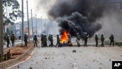 FILE: Riot police block the road near burning tires during a mass rally called by the opposition leader Raila Odinga over the high cost of living, Nairobi, Monday, March 27, 2023