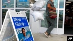 Un comprador pasa frente a un cartel que anuncia contrataciones mientras ingresa a una tienda minorista en Morton Grove, Ill., el 21 de julio de 2021.