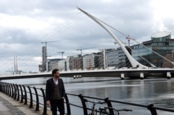 FILE - A man walks past offices in the Irish Financial Services Centre in Dublin, Ireland, Apr. 24, 2017.