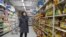 A shopper wearing a face mask browses an aisle of cooking oil in a supermarket in Beijing on March 16, 2020. 