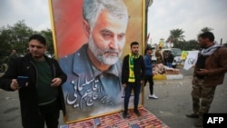 Supporters of Hashed al-Shaabi paramilitary force and Iraq's Hezbollah brigades pose with a poster of Iranian military commander Qasem Soleimani during a funeral for Soleimani and Iraqi paramilitary chief Abu Mahdi al-Muhandis, Jan. 4, 2020, in Baghdad.