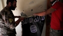 Anggota Pasukan Demokratik Suriah memegang bendera militan ISIS yang ditemukan di sebuah gedung di sebelah stadion di Raqqa, Suriah, 4 Oktober 2017. (Foto: REUTERS/Erik De Castro)