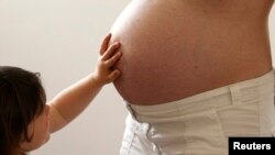 A child touches her pregnant mother's stomach at the last stages of her pregnancy in Bordeaux April 28, 2010.