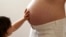 A child touches her pregnant mother's stomach at the last stages of her pregnancy in Bordeaux April 28, 2010.