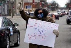 FILE - Ghana Goodwin-Dye signals to motorists participating in a drive-by rally to certify the presidential election results near the Capitol building in Lansing, Michigan, November 14, 2020.