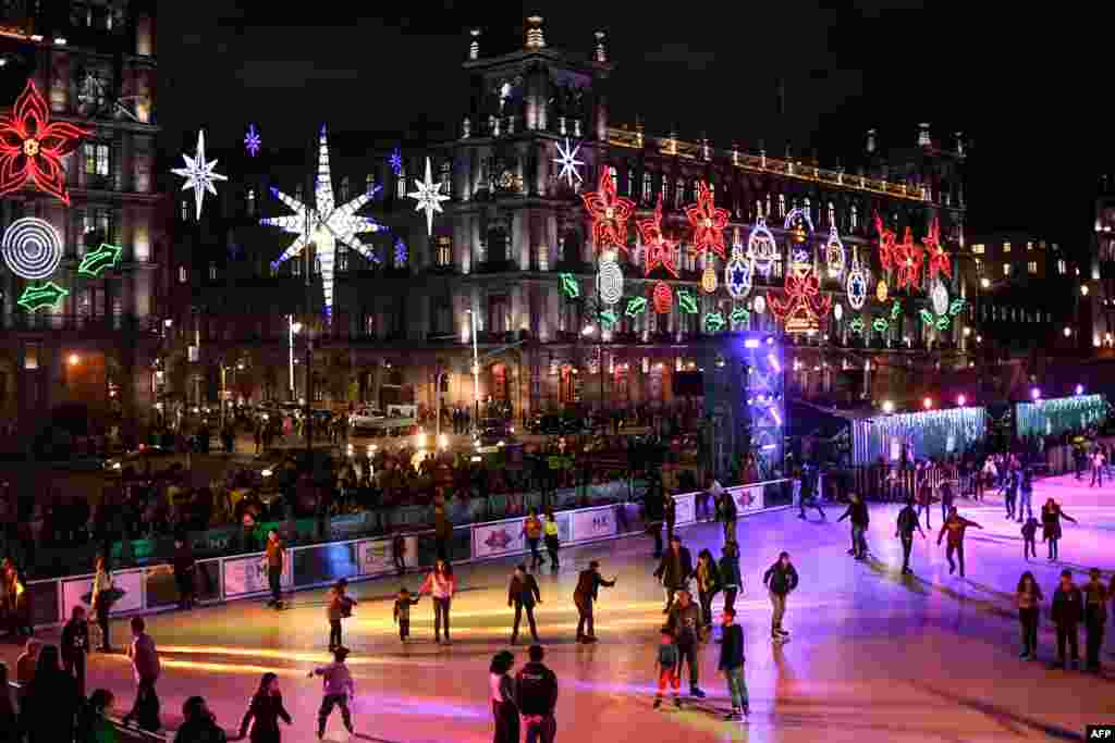 People skate on an acrylic rink placed in the Zocalo square with the City Hall showing Christmas decorations in the background in Mexico City, Dec. 17, 2019. 