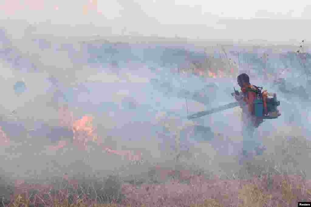 A man attempts to put out a fire following a rocket attack from Lebanon, amid cross-border hostilities between Hezbollah and Israel, in the Israeli-occupied Golan Heights.