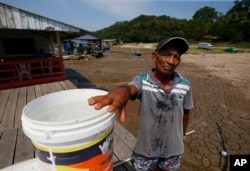 Raimundo Silva do Carmo, 67, shows the water he obtained from a well dug in the dry bed of Puraquequara Lake amid a severe drought, in Manaus, Amazonas state, Brazil, Thursday, Oct. 5, 2023. (AP Photo/Edmar Barros)