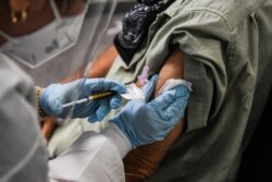 FILE - A man receives a trial COVID-19 vaccine at the Research Centers of America, in Hollywood, Florida, August 13, 2020.