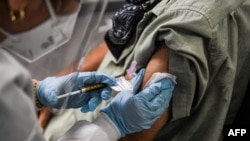 FILE - A man receives a trial COVID-19 vaccine at the Research Centers of America, in Hollywood, Florida, Aug. 13, 2020. 