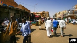 People walk in front of shops at a market in the Sudanese capital, Khartoum, Feb. 21, 2021. Sudan has ratified U.N. conventions against torture and enforced disappearances, after months of delay. 