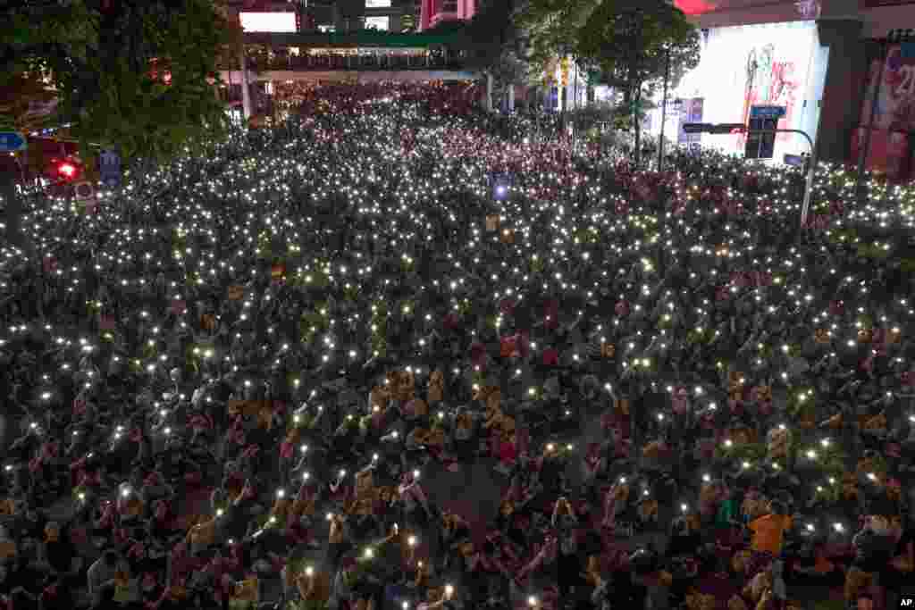 Pro-democracy protesters hold up flashlights on the phones during a rally in the central business district in Bangkok, Thailand.