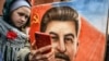 RUSSIA -- A woman, next to a girl, holds a portrait of Soviet leader Josef Stalin and takes a selfie at his grave outside the Kremlin on the Red Square in Moscow, March 5, 2019