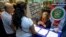 FILE - In this June 24, 2017 photo, Camelia Santiago, administrative assistant with the Puerto Rico Federal Affairs Administration gives out information to a couple during an orientation session for newly arrived Puerto Ricans in Orlando, Fla.