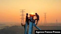 Employees work on a high voltage transmission tower in Yichun, in China's central Jiangxi province, Sept. 28, 2021.