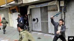 An Iranian opposition protester (l) runs from a member of the security forces with a baton during clashes in Tehran on 27 Dec. 2009.