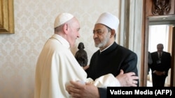 This photo taken and handout on October 4, 2021 by The Vatican Media shows Pope Francis (L) greeting Egyptian Islamic scholar and the current Grand Imam of al-Azhar mosque, Sheikh Ahmed Al-Tayeb upon his arrival for a private audience at The Vatican, with