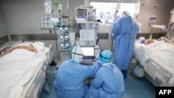 Medical staff treat COVID-19 coronavirus patients at a hospital in Wuhan, in China's central Hubei province, March 19, 2020.